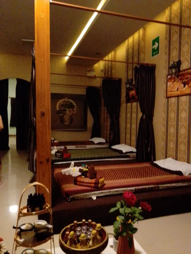 Thai massage mats under wooden beams with a flower and tea tray in the front room, Chiang Mai