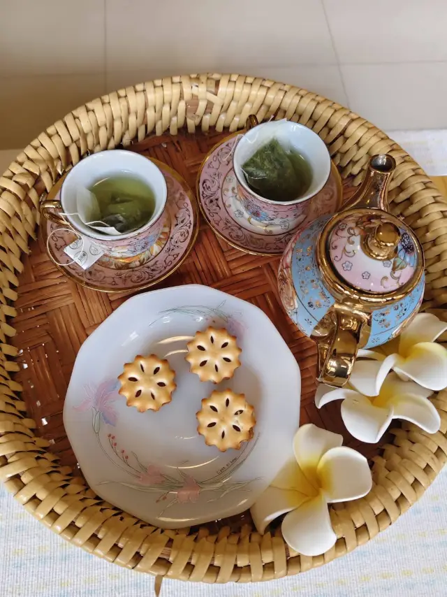 Tray of green tea cups, biscuits and plumeria flowers offered to guests in Chiang Mai