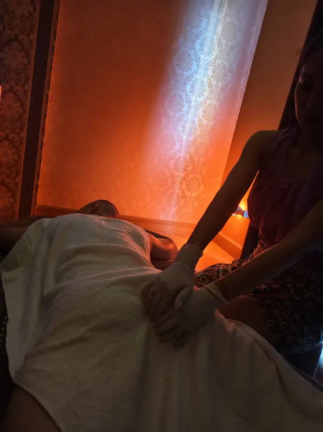 Therapist's hands massaging a guest covered with a towel in a softly lit room in Chiang Mai