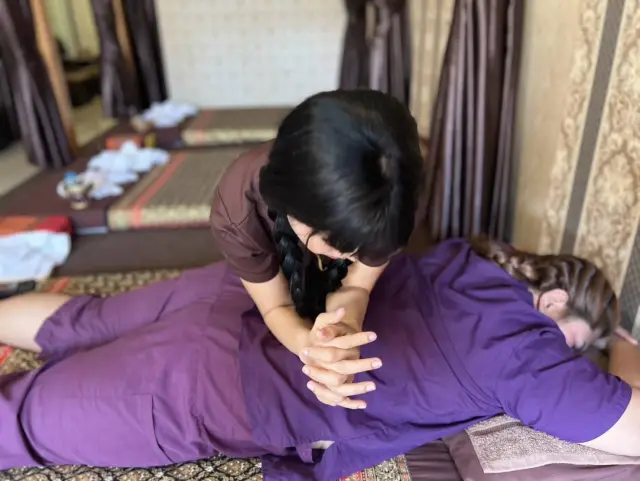 Therapist giving a Thai massage to a guest in purple clothing on a floor mat in Chiang Mai