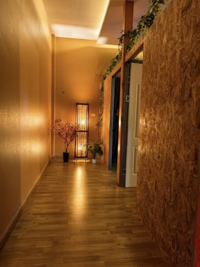 Warm-lit hallway with wood flooring leading to the massage rooms at Ai Oon Massage Lanna